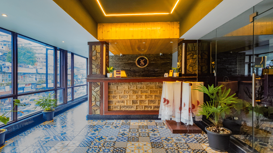 The front desk of Sumitel JB park, Darjeeling, with modern interiors, patterned tiles, indoor plants, and glass windows