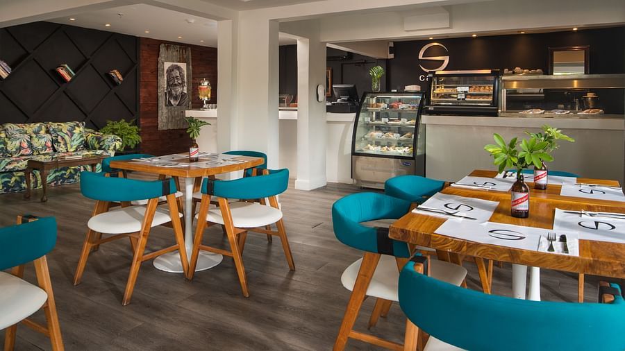 A chic cafe at our hotel in Jamaica with cosy chairs placed around wooden tables - S Hotel Montego Bay, Jamaica