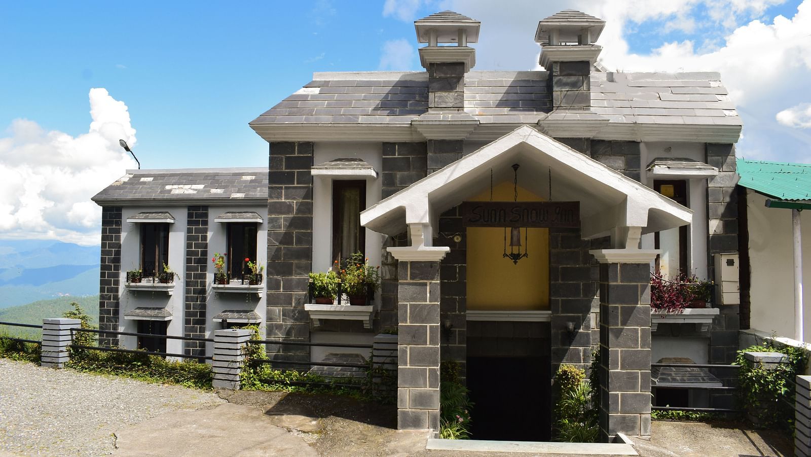 Traditional stone building with a wooden door and a balcony overlooking the mountains.