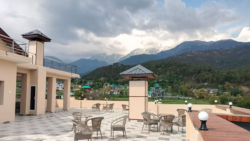 Outdoor terrace with tables, chairs, and mountains.