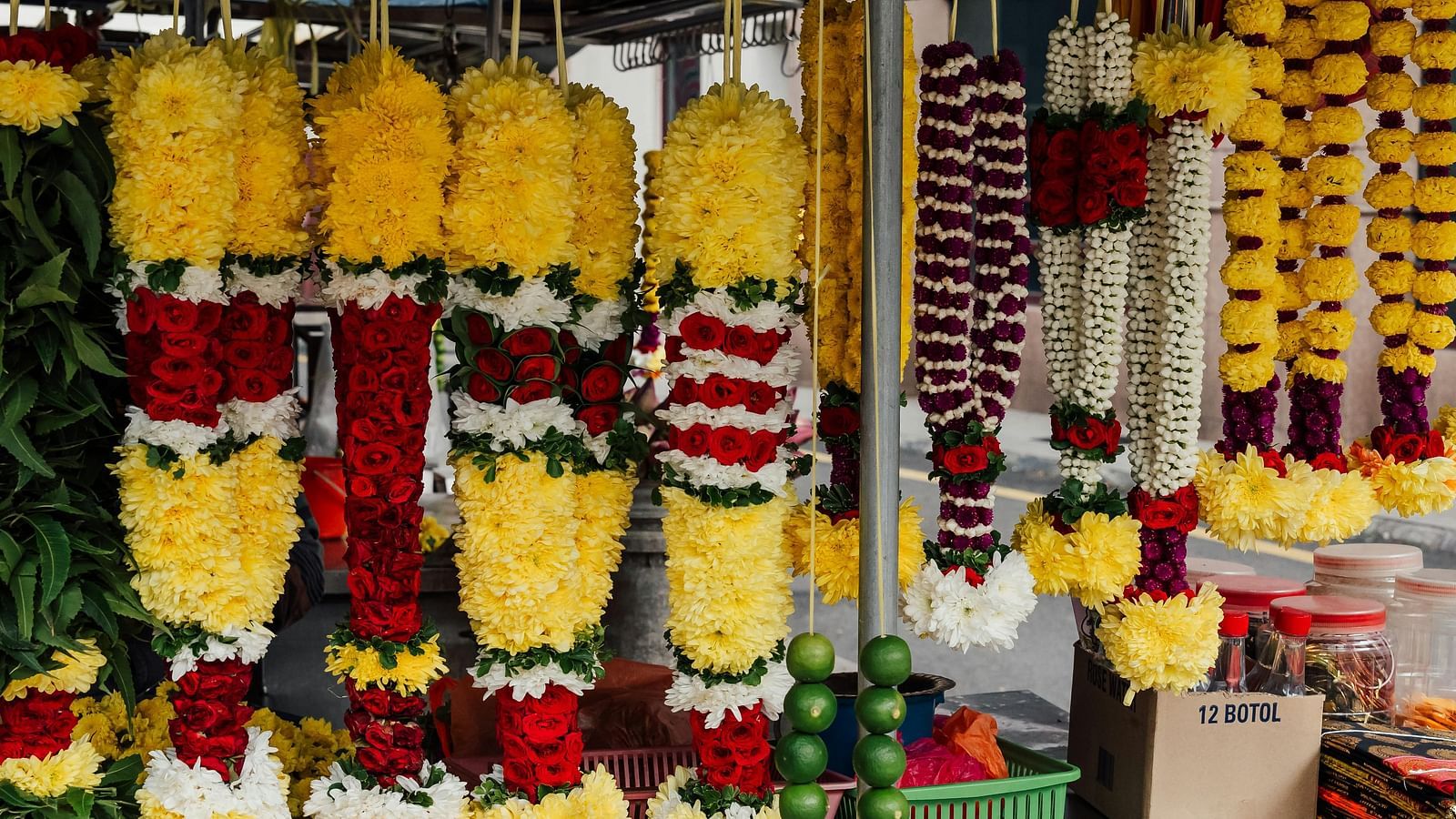 An image of vibrant display of colourful flower garlands hanging in a shop.
