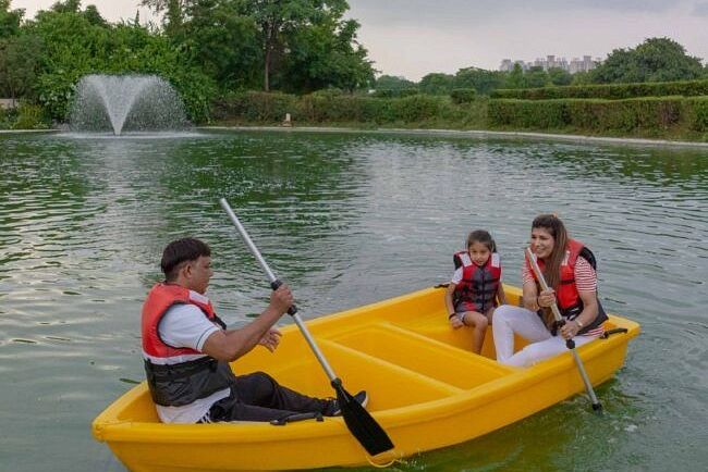 Group of people paddling a bright yellow boat in a lake with a water fountain in the background at Karma Chalets.