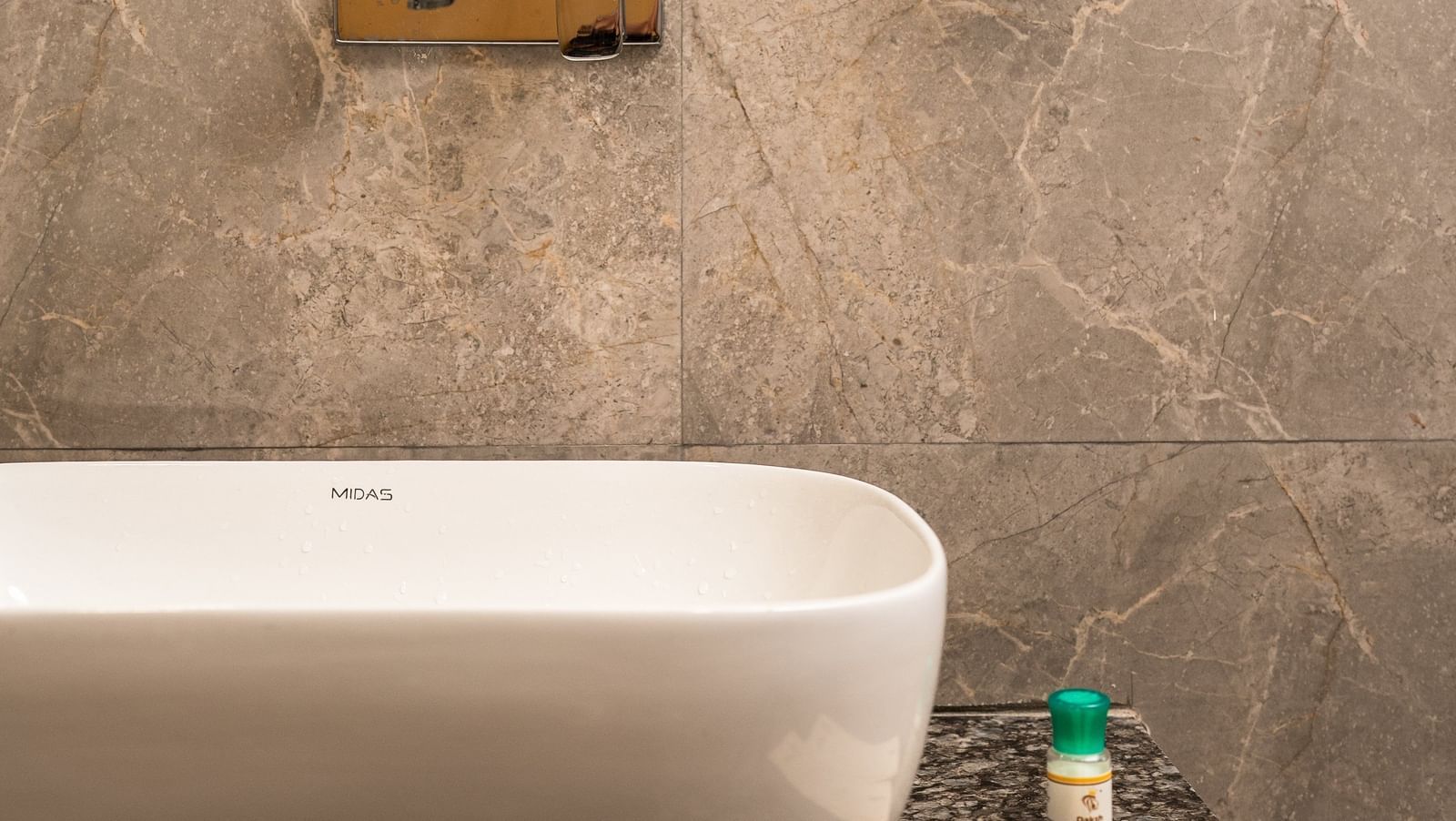 A modern bathroom at Daksh The Grand Gowardhan, Dwarka, featuring a stylish wash basin and grey tiles along with a mirror mounted over it.