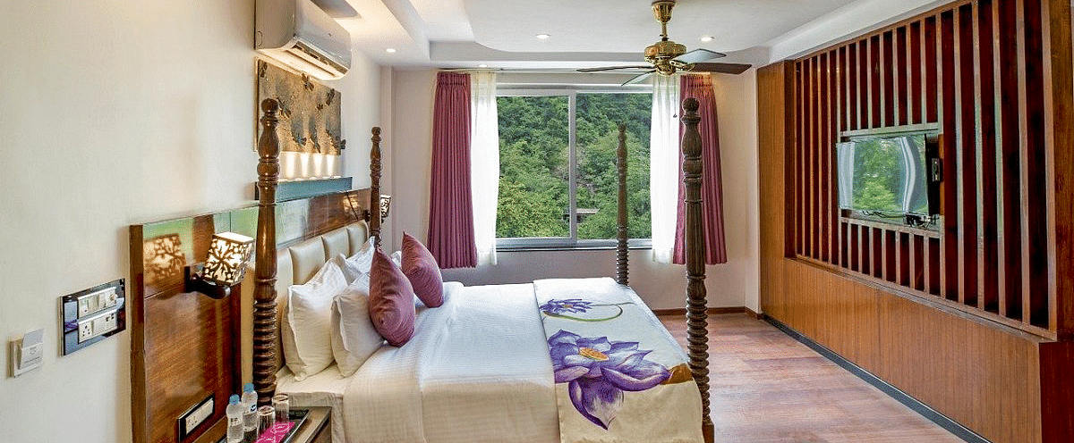 Side view angle of a bedroom with a double bed with bed side tables besides it at Regenta Inn DLS.