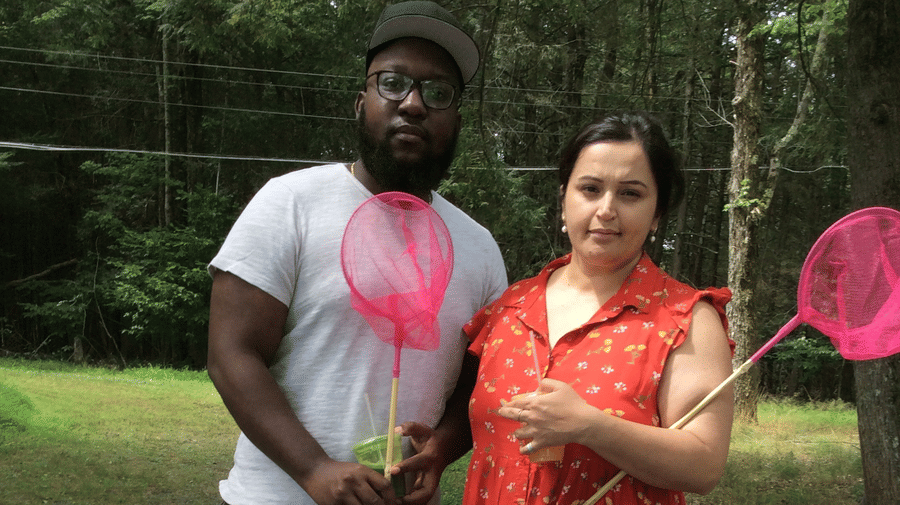  A man and woman, standing outdoors, each holding a pink butterfly net, with a table in front of them at YO1 Longevity & Health Resorts, Catskills