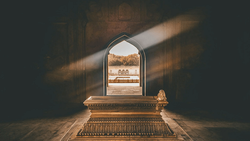 Image of a beam of sunlight shining through an arched doorway featuring a tomb inside the chamber - The Dukes Retreat, Khandala