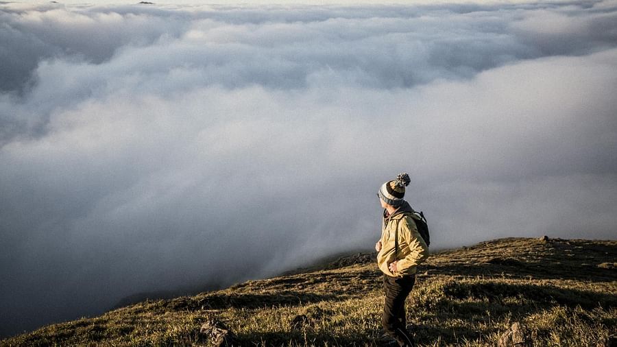 Image of a person standing on a mountain top overlooking a thick blanket of clouds - The Dukes Retreat, Khandala