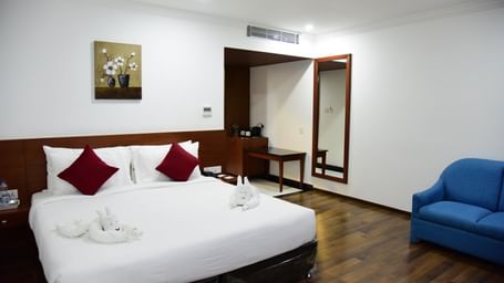 A bright and modern studio room at The Royal Comfort, featuring a comfortable bed with white linens and a stylish teal runner, along with a sleek workspace.