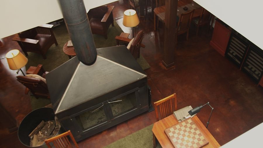 Overhead view of a central fireplace with a chimney, surrounded by wooden chairs and tables - Brewery Gulch Inn & Spa