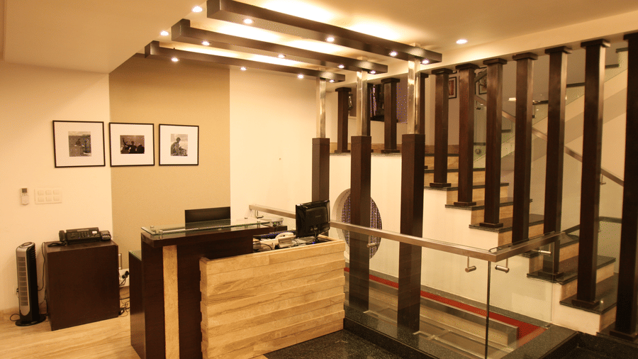 Reception desk at Emblem Hotel, New Friends Colony, New Delhi featuring a computes and a telephone at the desk, and a flight of stairs leading to the floor above. 