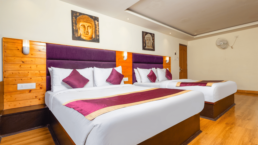 Comfortable Sumitel Hotels room featuring twin beds, rich wooden ceiling, stylish lighting, vibrant accents, and a clean, spacious layout perfect for family stays.