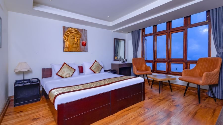 Guest room at Sumitel Premier Inn, Siliguri, with a large bed, cushioned chairs, big windows, and soothing décor designed for a relaxing stay experience.