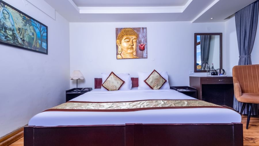 Cosy room at Sumitel Premier Inn, Siliguri, with a neatly made double bed, wall painting, wooden flooring, and stylish interiors for a pleasant stay.