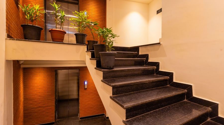Indoor staircase at Sumitel Premier Inn, Siliguri, with potted plants, warm lighting, and a modern layout that creates a fresh and stylish ambience.