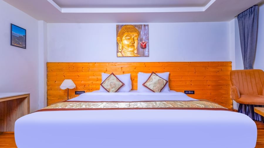 Elegant bedroom at Sumitel Premier Inn, Siliguri, with a large bed, soft lighting, wall art, and wooden accents creating a warm and inviting atmosphere.