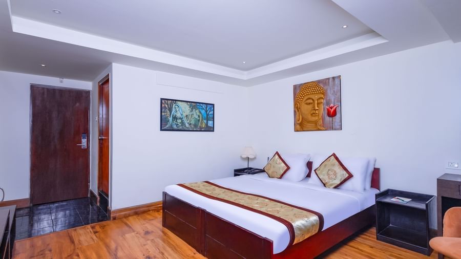 Guest room at Sumitel Premier Inn, Siliguri, with a double bed, wall décor, wooden flooring, and warm lighting offering a comfortable and inviting stay.