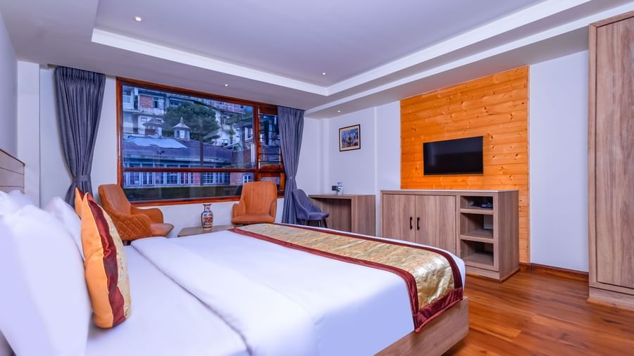 Spacious guest room at Sumitel Premier Inn, Siliguri, with twin beds, wall-mounted TV, work desk, and large window offering a comfortable stay experience.