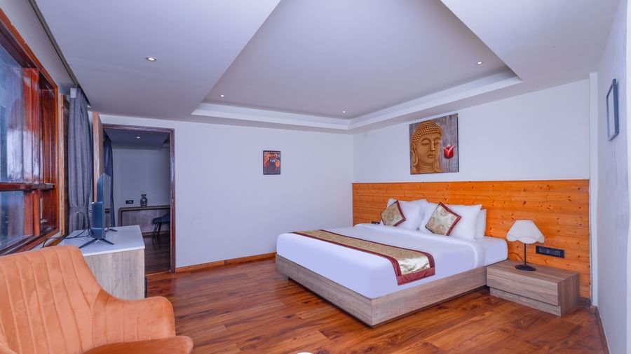 Spacious guest room at Sumitel Premier Inn, Siliguri, featuring a cosy double bed, wooden flooring, warm lighting, and seating chairs for a relaxing stay.