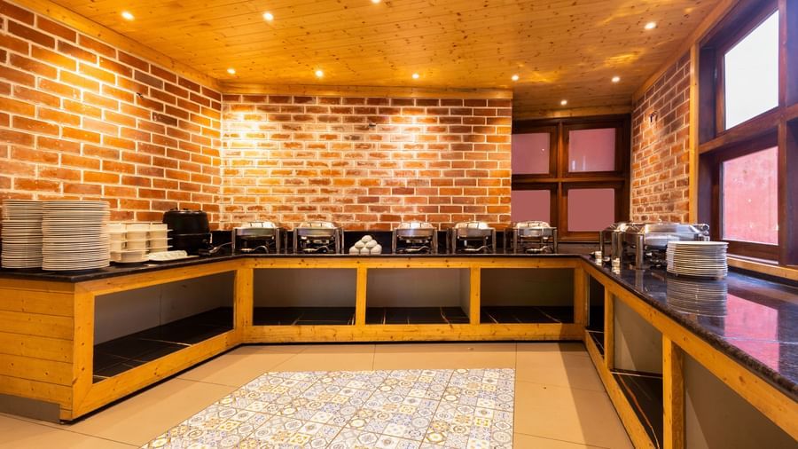 Buffet counter at Sumitel Premier Inn, Siliguri, designed with brick walls, bright lighting, and neatly arranged counters offering a modern dining atmosphere.
