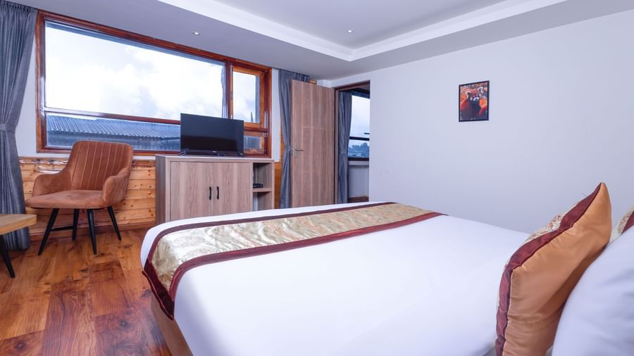 Bedroom view at Sumitel Premier Inn, Siliguri, highlighting a neatly made bed, large windows, and wooden interiors that create a bright and comfortable atmosphere.