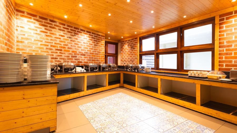 Buffet counter at Sumitel Premier Inn, Siliguri, with brick wall design, warm lighting, and spacious counters for serving freshly prepared dishes to guests.