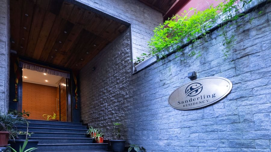 Entrance view of Sumitel Premier Inn, Siliguri, with a stone wall, greenery, and the property’s nameplate creating a warm and inviting arrival experience.