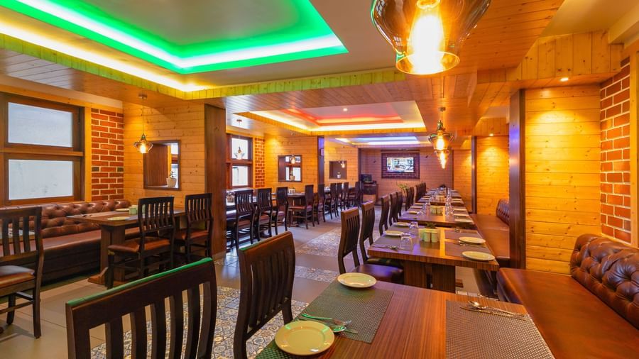 Restaurant at Sumitel Premier Inn, Siliguri, with wooden interiors, stylish ceiling lights, neatly arranged tables, and a warm ambience for an enjoyable dining experience.