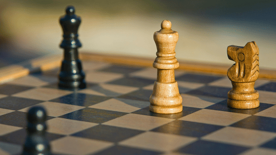 A close-up shot of a chess board with several chess pieces scattered on it.