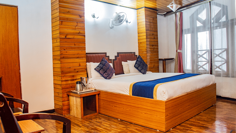 Hill Super Deluxe Room at Central Hill Resort in Gangtok featuring a plush bed next to a large window on a wooden flooring