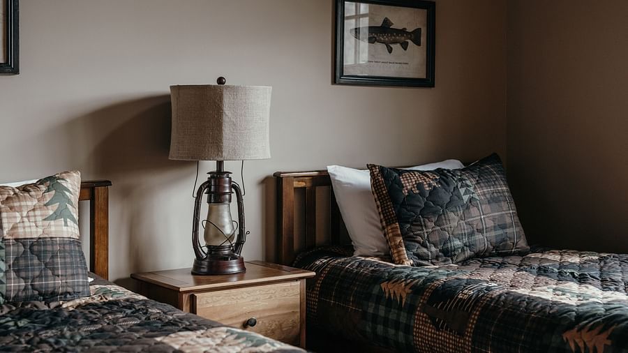 Twin beds with a lamp and side table in between inside a hotel.