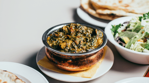 a bowl served with Indian curry and naan 