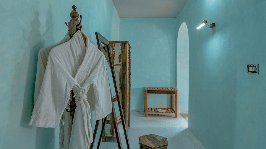 An image of a bathrobe hanged in a corner of the room where there is also a wardrobe