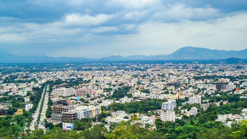 an aerial view of the city of Tirupati with buildings and a small hill in the background