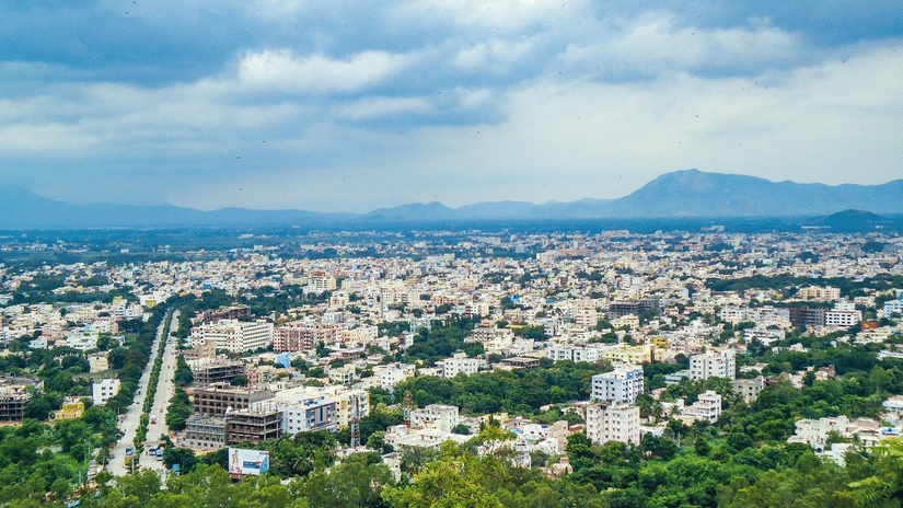 an aerial view of the city of Tirupati with buildings and a small hill in the background. A trip from Bengaluru to Tirupati via car is the best way to travel to this holy city.