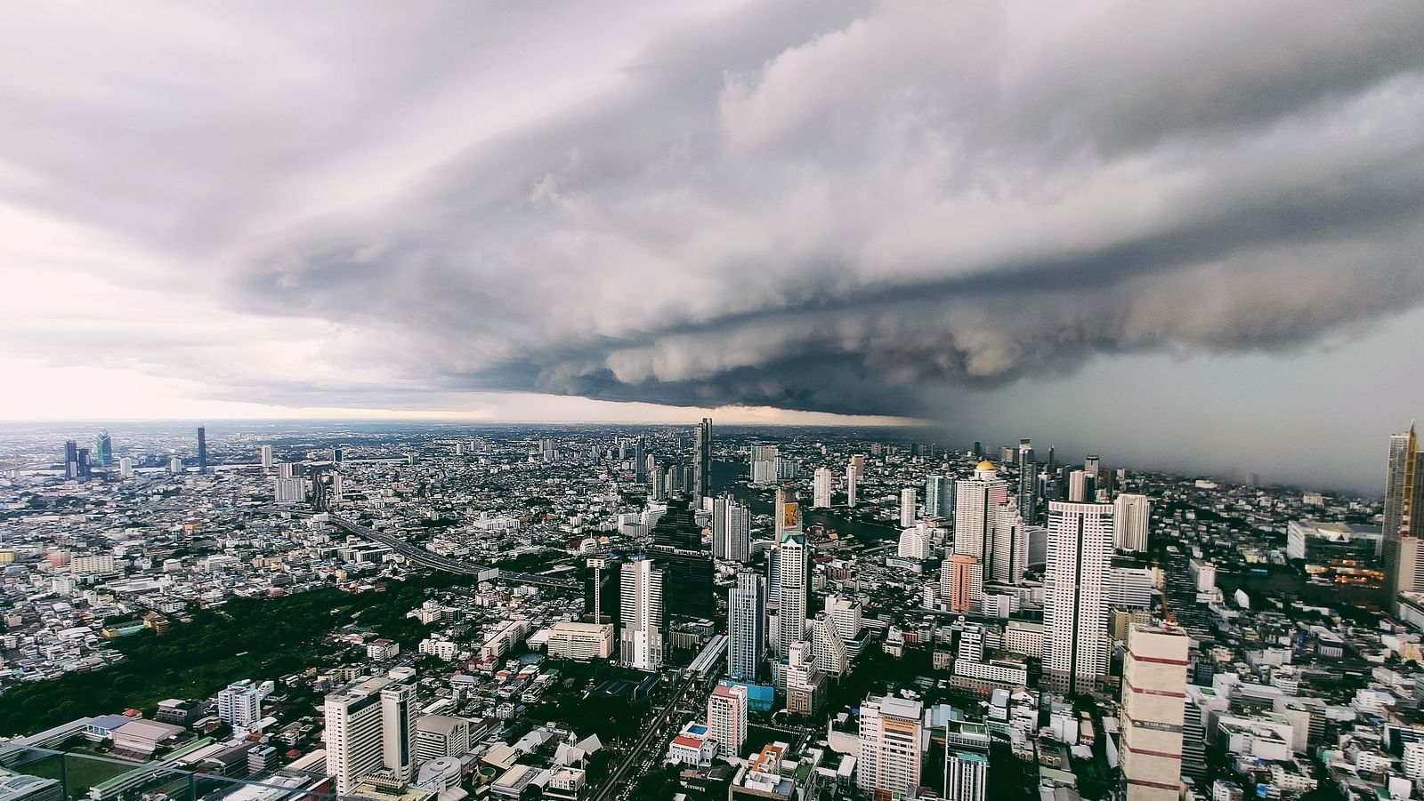 a mighty cloud covering the city of bangkok with part of the city being drenched in rain.