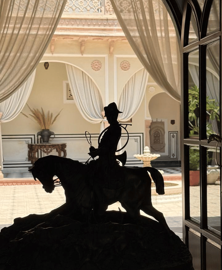 A silhouette of a person seated gracefully on horse statue surrounded by draped curtains - Khas Bagh, Jaipur.