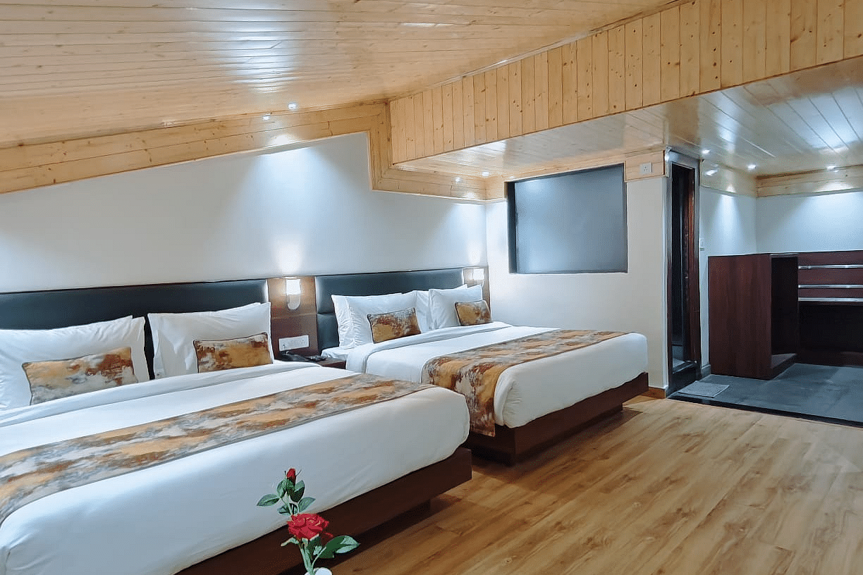 A hotel room with two beds, a side table and a wood ceiling highlighting the room's design and furnishings - Sumitel JB Park, Darjeeling