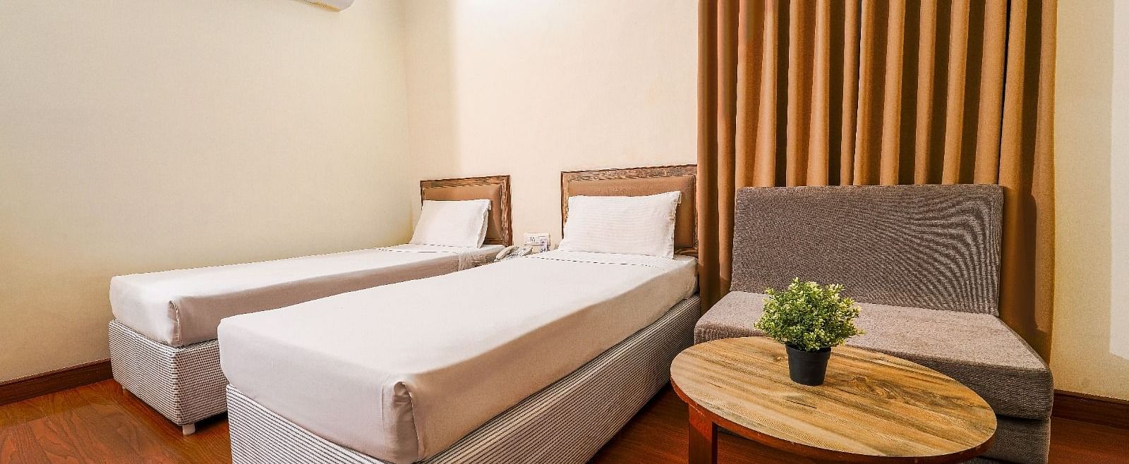 Hotel room with two single beds, a comfortable couch, and a coffee table in Hyderabad near Ramoji Film City.