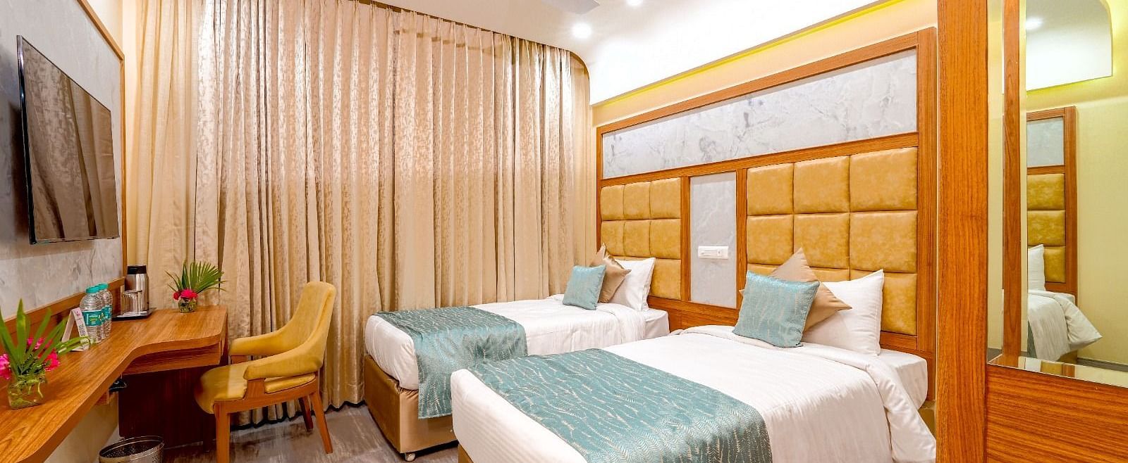 omfortable twin beds in a stylish hotel room, featuring soft lighting, a workspace, and large windows at Tara, Comfort Hotel in Hyderabad - Ramoji Film City.