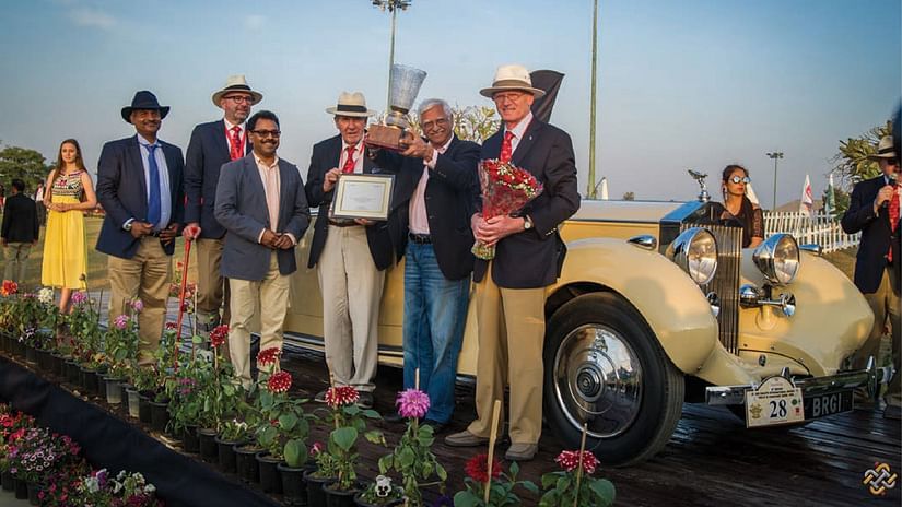 A group of people posing for a picture next to a vintage car - Karma Lakelands.