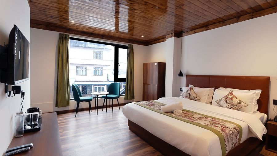 a side view of the premium room with a large bed, a TV and a balcony at Mystique Valley Resort 