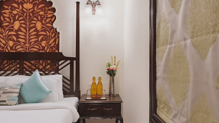 A view of a bed with a wall art, pendant lights, a bedside table featuring a partially visible soft patterned beige wall art.