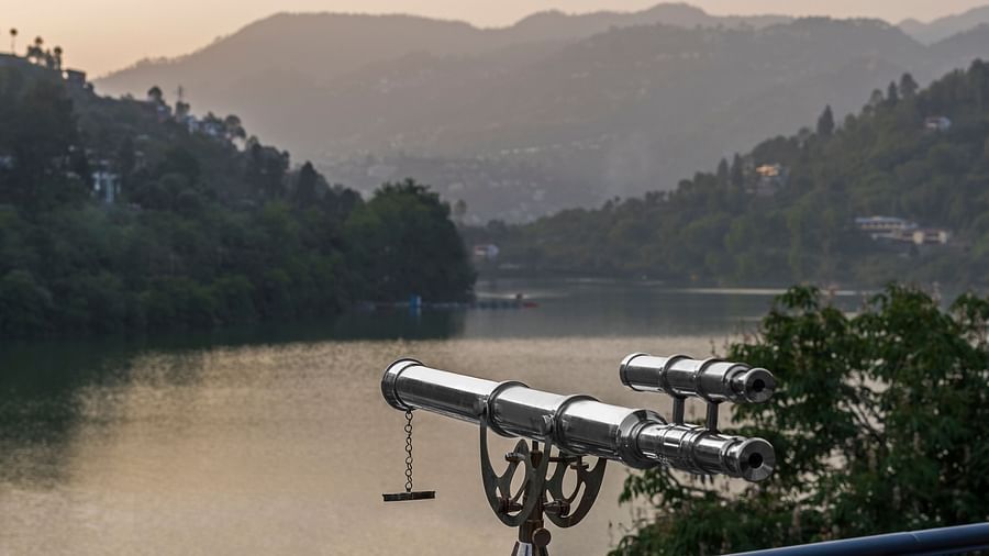 binoculars set up near a picturesque lake, with hills in the background, ideal for nature observation.