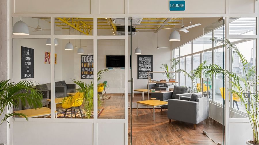 An image of a lounge area from outside, featuring sofas and bean bags for relaxation, coffee tables, and a bookshelf stocked with a selection of books to read.