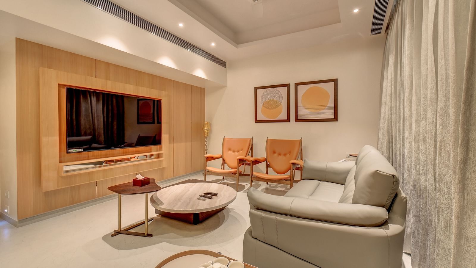 A sofa with a coffee table in front, two chairs on the side, and a TV unit facing the seating area