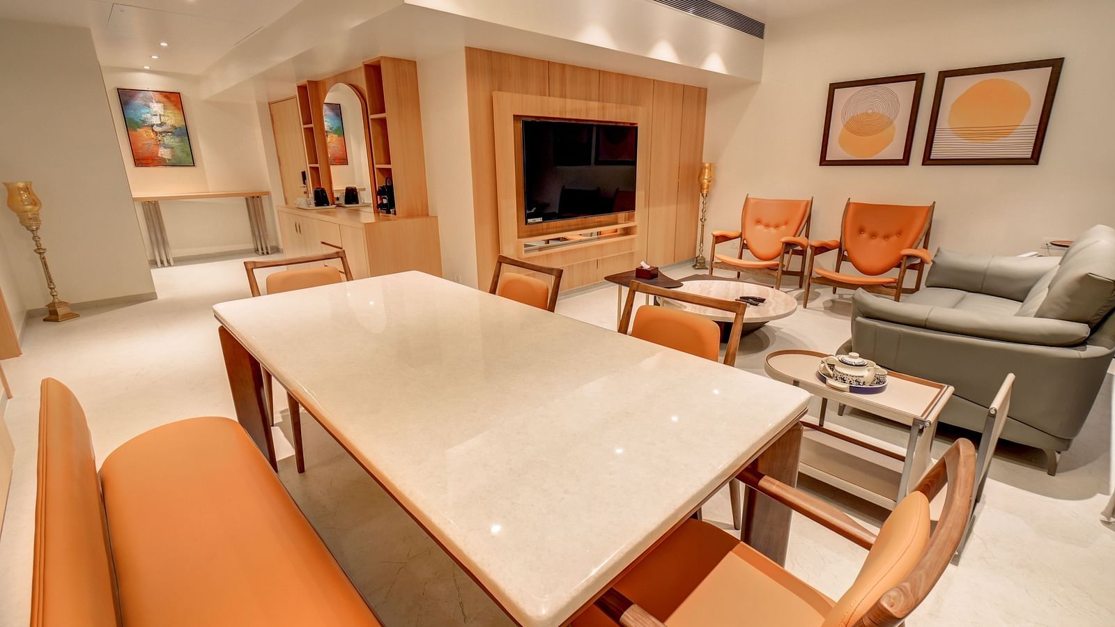 A cosy living area with a table and chairs arranged around it, a sofa seating area on the side, and a TV unit positioned in front