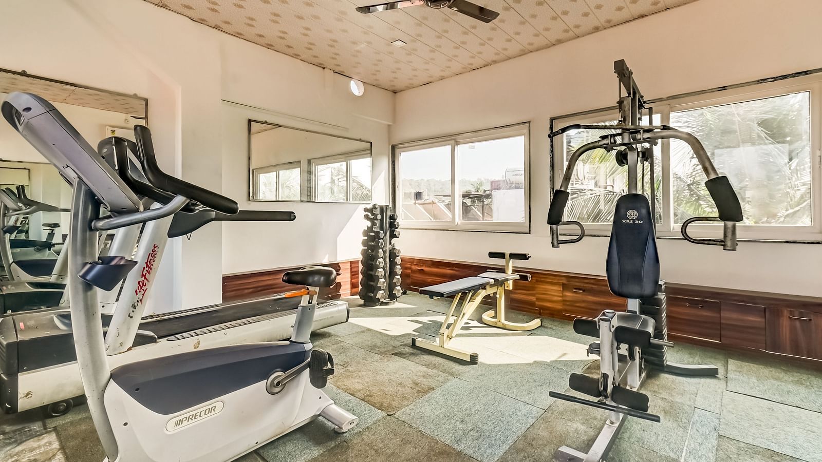  A gym with equipment neatly arranged and maintained, featuring large windows that flood the room with natural light