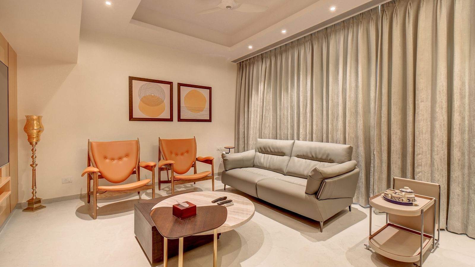 A living area with a sofa, coffee table, chairs, and two portraits on the wall