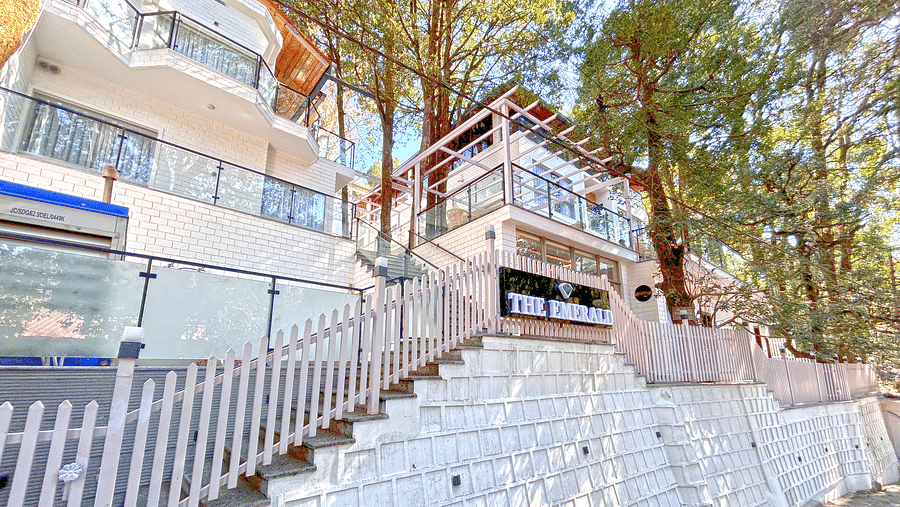 A facade image of DLS The Emerald, Nainital surrounded by tress and lush greenery