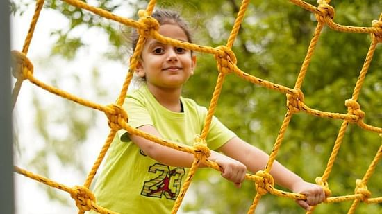 Kid on a commando net ride at inflated trampoline surrounded by trees at Themis Mudhouse - A Nature's Retreat Resort & Wellness